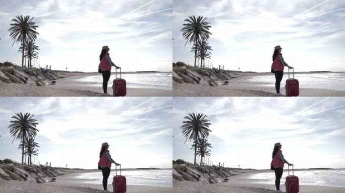 带行李箱的旅行女人站在海边的海岸线上，旅行概念，复制空间