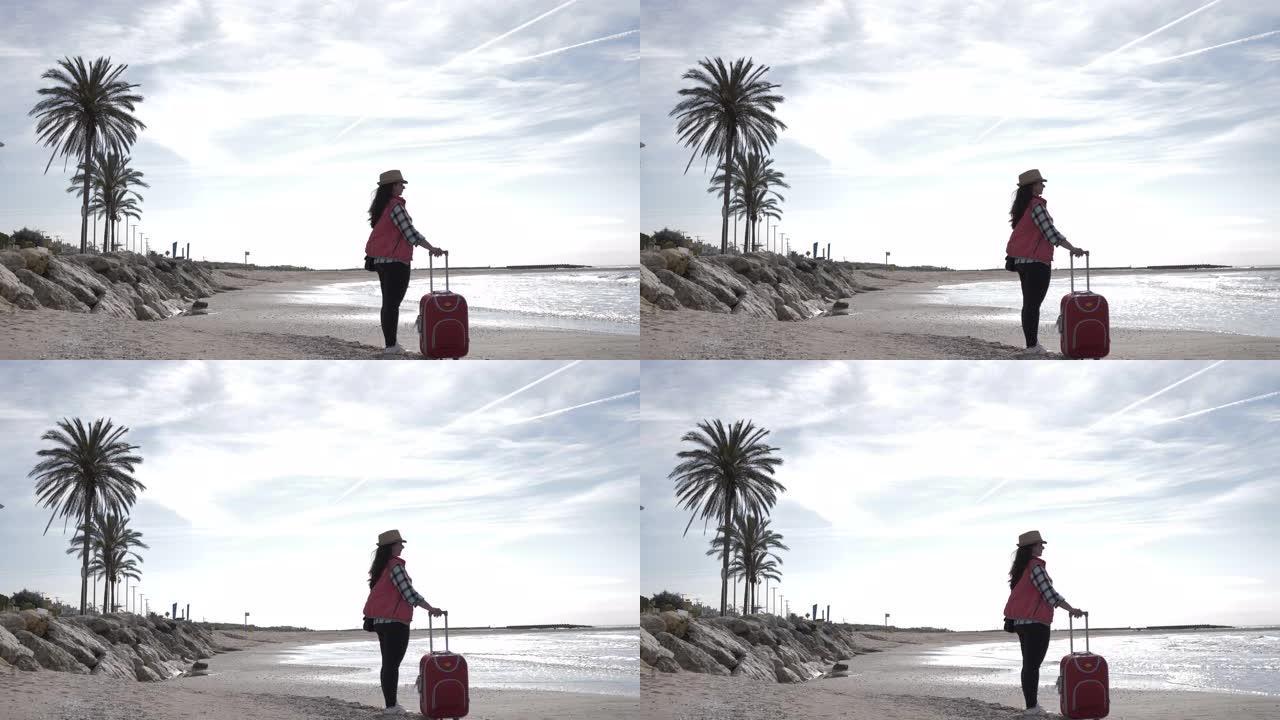 带行李箱的旅行女人站在海边的海岸线上，旅行概念，复制空间