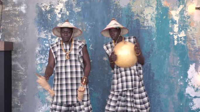 两名穿着五颜六色服装的非洲艺术家演奏djemba鼓