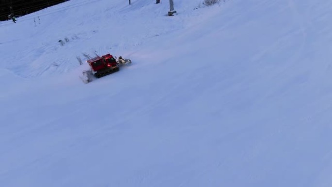 现代红色雪猫在滑雪缆车下驶向白色轨道