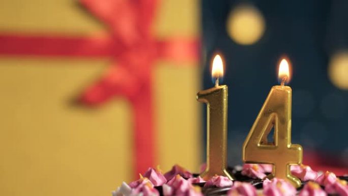 生日蛋糕14号点火器燃烧的金色蜡烛，蓝色背景礼物黄色盒子用红丝带绑起来。特写和慢动作