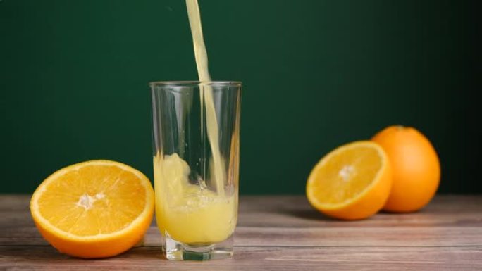将新鲜的黄色果汁倒入带有橘子的木制桌子上的高杯中。橙汁、苏打水或柠檬水。自制果汁。有机维生素饮料。慢