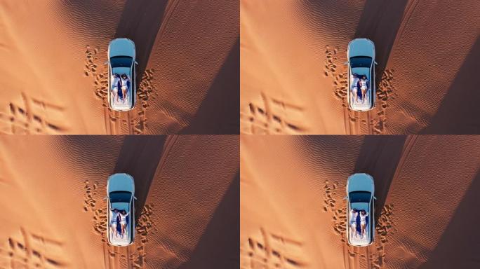 空中。年轻夫妇在沙漠的车顶上放松的俯视图。