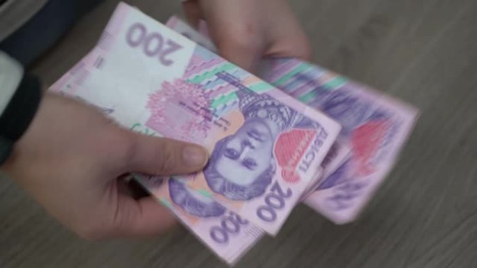 女人的手数乌克兰的钱。木制桌子背景上的乌克兰格里夫纳。女孩算格里夫纳。