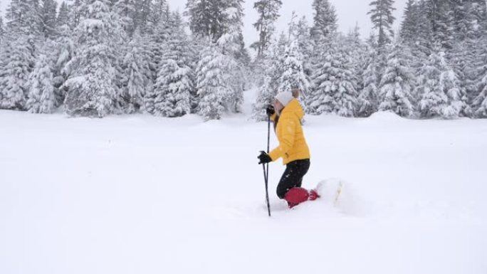 冬季旅行者。一名年轻女子的慢动作游客雪鞋在深雪中行走，享受着冬日的高山。