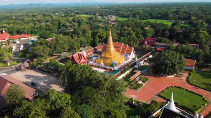 4k空中无人机拍摄-晴天的泰国佛教寺庙，绿树和灌木丛环绕的金色宝塔，橙色屋顶瓦，泰国佛教wat，宗教