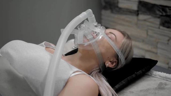 女孩躺在床上，戴着人工呼吸面罩