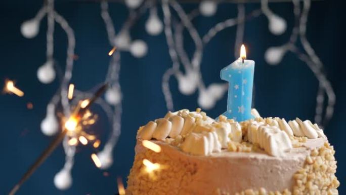 生日蛋糕，带有1号蓝色蜡烛和蓝色背景上的烟火。慢动作和特写视图