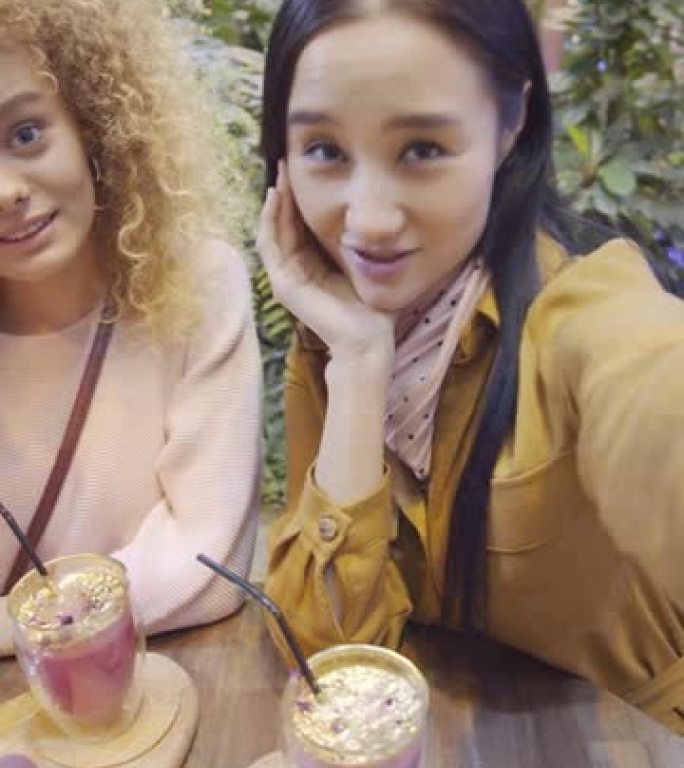 两个年轻开朗的女人在咖啡馆里挥舞着对着镜头说话