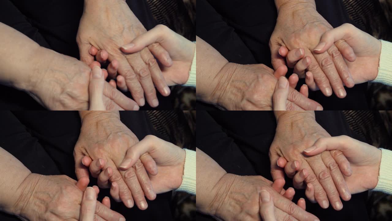 一只年轻女性的手在户外安慰老年老妇的手臂。孙女和祖母在一起。关心和爱的概念。侧视图慢动作