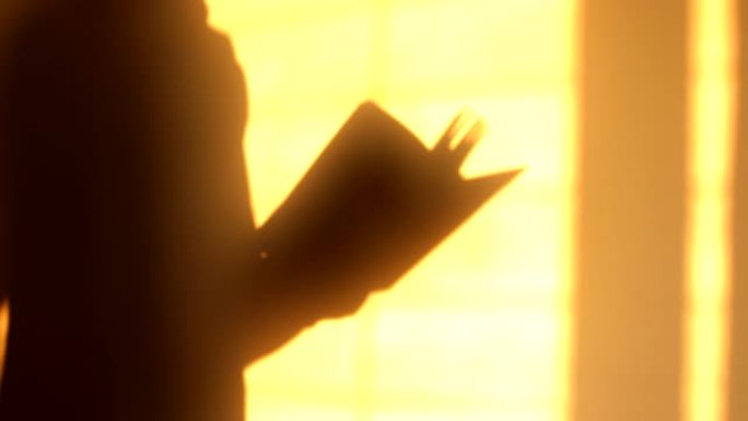 男人在橙色墙上看书的影子