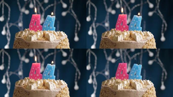 蓝色背景上有44号粉色蜡烛的生日蛋糕。蜡烛吹灭了。慢动作和特写视图