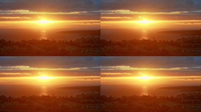 海面上的橙色日落。日落或黎明时，五颜六色的阳光和眩光笼罩着海洋附近的城市，大片的太阳盘和戏剧性的云层