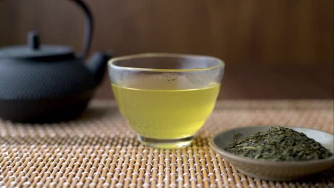 带茶壶和叶子的玻璃杯中的热日本绿茶