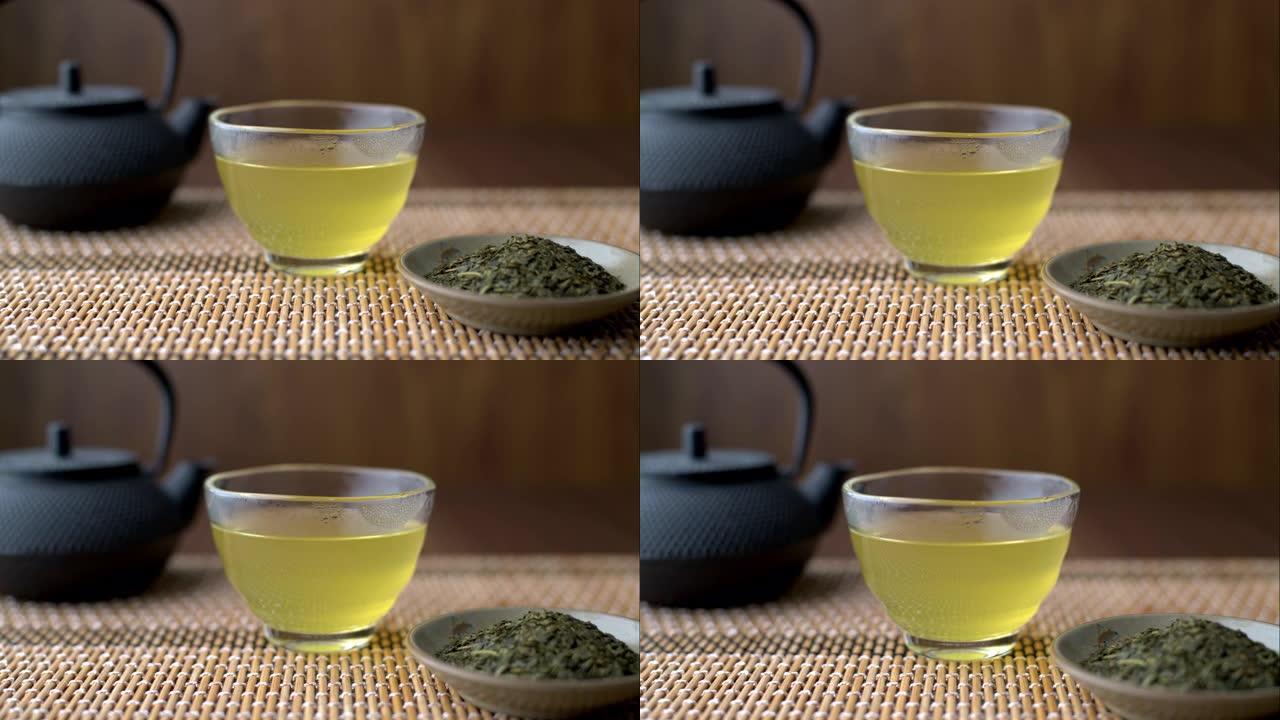 带茶壶和叶子的玻璃杯中的热日本绿茶