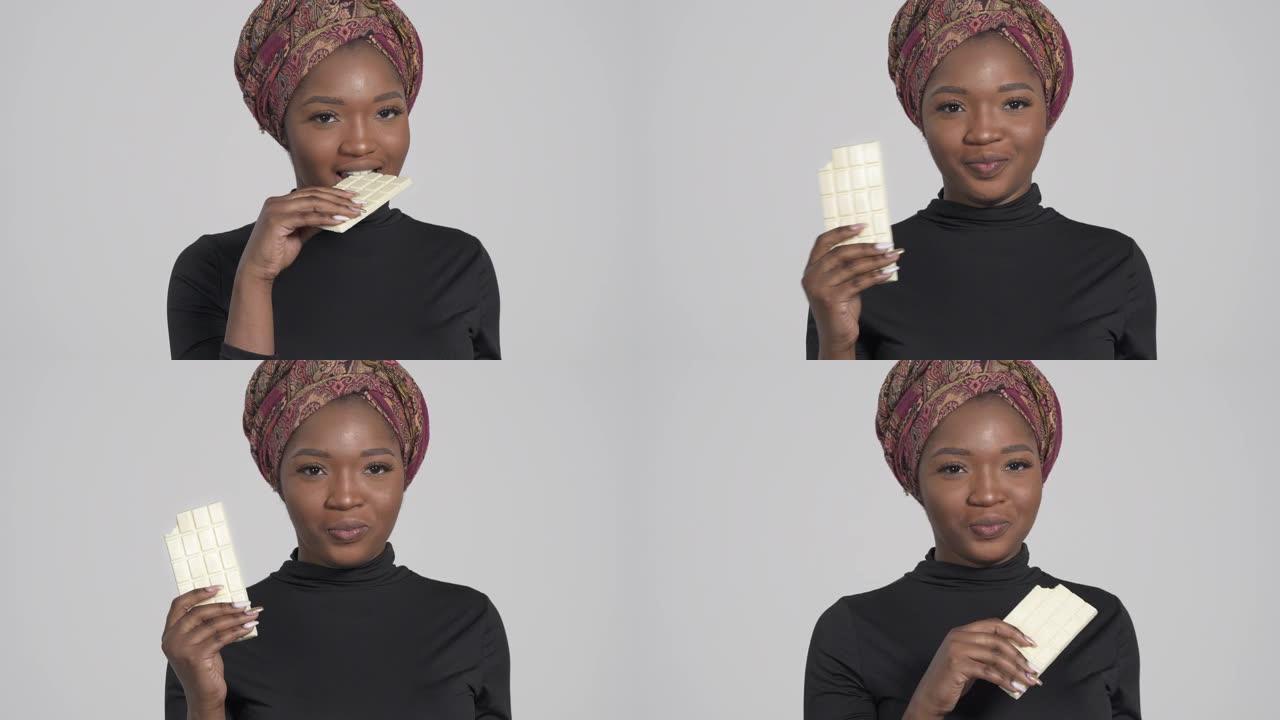 年轻迷人的非洲女人吃一盘白巧克力。孤立，在白色背景上
