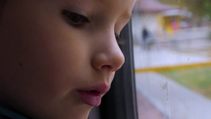 孩子在窗户里倒影，玻璃。一个孩子在火车上向窗外看的特写镜头。坐火车旅行。这个男孩看着跑步的风景。春天