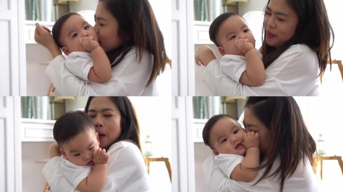 亚洲年轻的成年母亲在客厅亲吻快乐的儿子。母亲的爱概念。