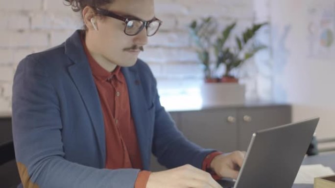 年轻的创业者独自在办公室用笔记本电脑打字