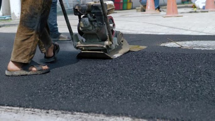 工人使用地面压实机施工道路