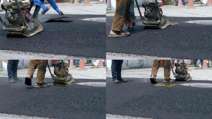 工人使用地面压实机施工道路