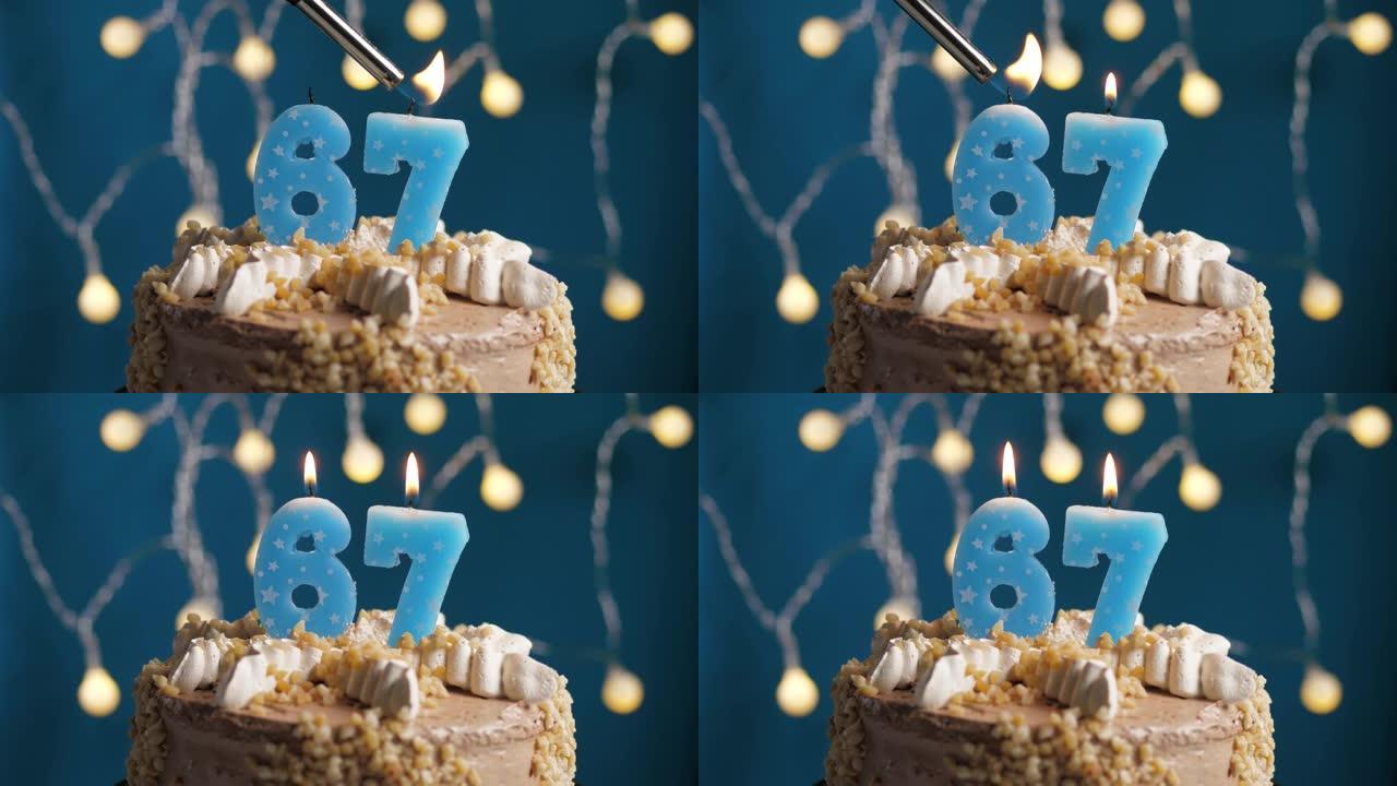 蓝色背景上有67号蜡烛的生日蛋糕。蜡烛着火了。慢动作和特写视图