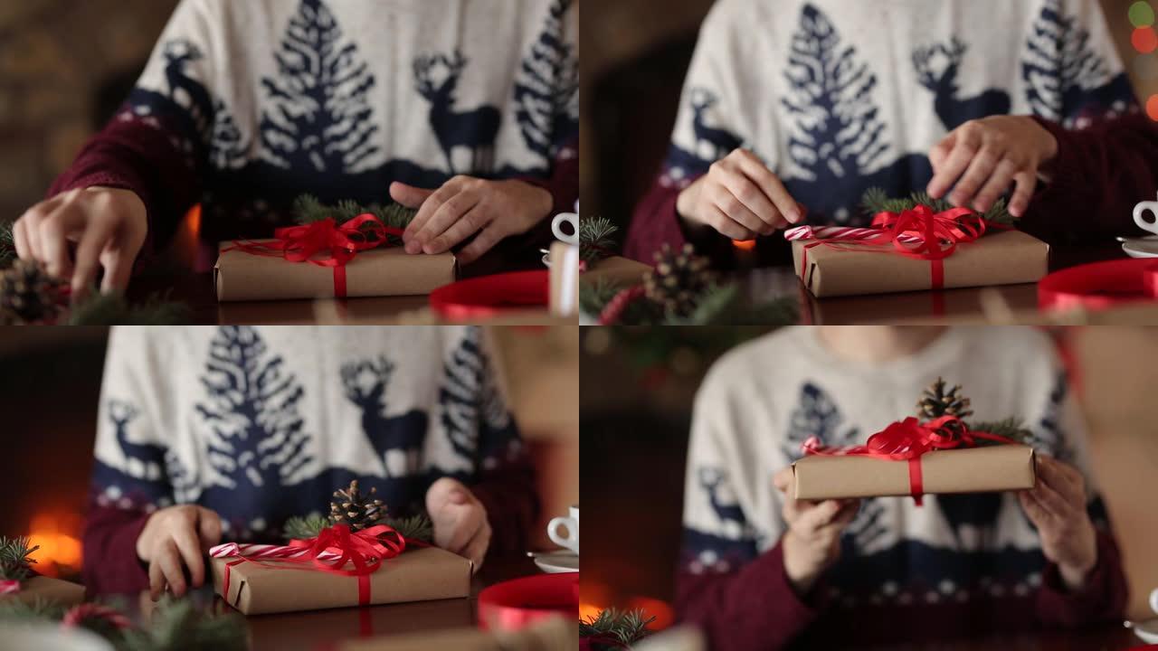 男人的双手在壁炉附近的圣诞节礼物上系蝴蝶结，包装盒，用杉木树枝，圆锥体，藤糖装饰在桌子上，然后向相机