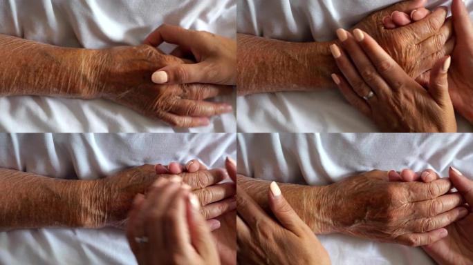 女人拿着和温柔抚摸生病母亲的手给予支持。女儿安慰躺在医院床上的年迈妈妈皱巴巴的手臂。关心或爱的概念。