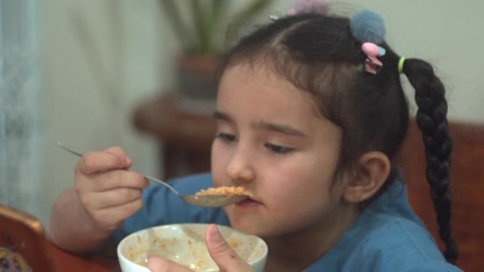 一个女孩坐在家里的客厅里吃饭