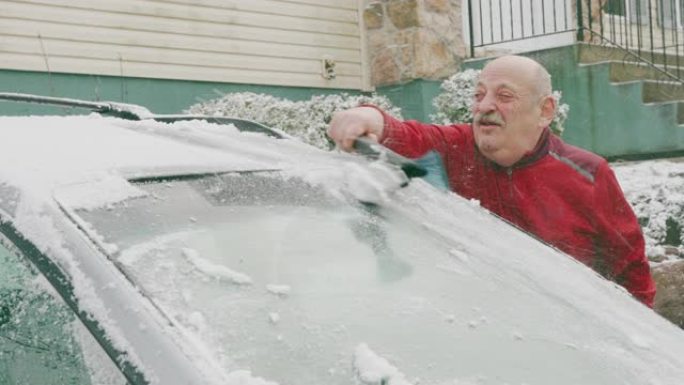 69岁的老人在冬天从雪中清洗汽车。