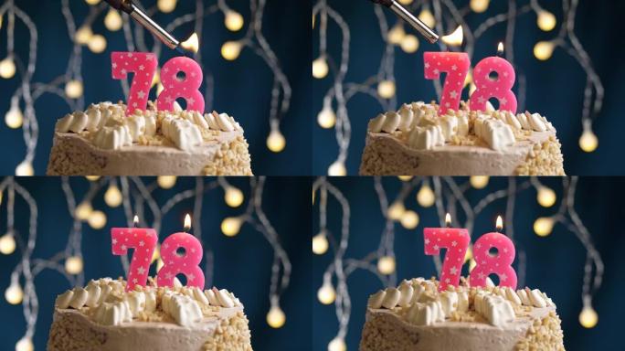 蓝色背景上有78号粉色蜡烛的生日蛋糕。蜡烛着火了。慢动作和特写视图