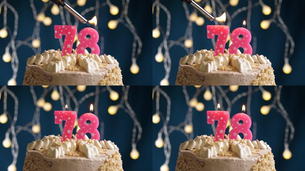 蓝色背景上有78号粉色蜡烛的生日蛋糕。蜡烛着火了。慢动作和特写视图