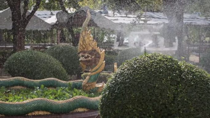 洒水器在亚洲花园喷水，背景是龙雕像
