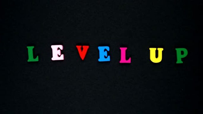 由木制五彩字母组成的单词 “level up”。五颜六色的单词循环。
