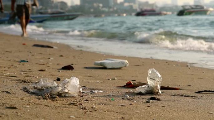 人们带着塑料橡胶在海滩上行走，废物留在海滩上，海浪把它们吹入大海