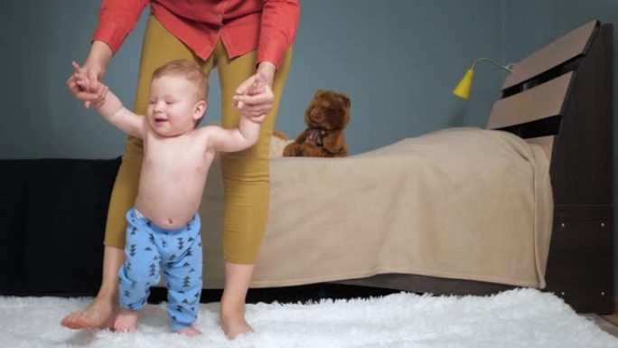 妈妈带领婴儿牵着他的手走向镜头。第一个婴儿台阶概念。慢动作
