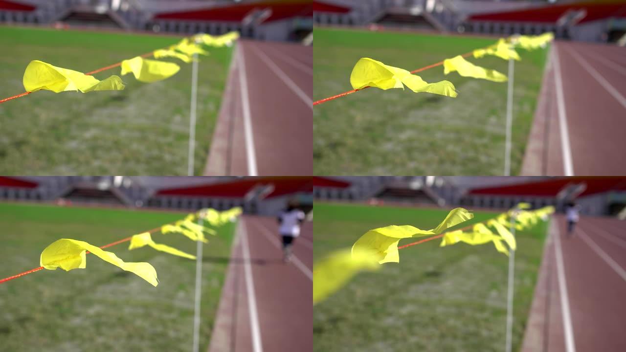 体育场的跑道。焦点在飘扬的黄旗上。主题在左边。