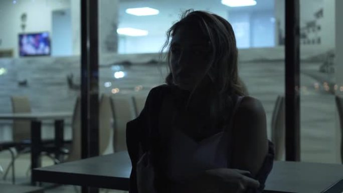 一个孤独而悲伤的女孩在明亮的陈列柜的背景下剪影