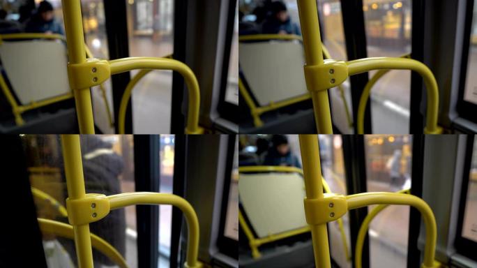 公共汽车停在车站，玻璃门打开，一个人进入机舱。从公共汽车里面看。不露面。黄色扶手的特写。背景模糊。抽