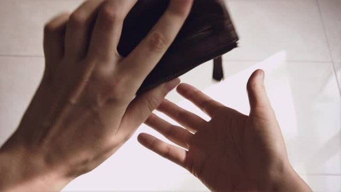 年轻人检查一个没有钱的钱包，然后愤怒地把它扔在地板上