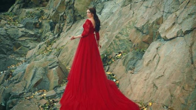 穿着红色连衣裙的女人长火车岩石山。后视图向后看