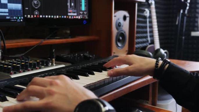 词曲作者音乐家工程师在家庭录音棚里演奏midi键盘钢琴，配有监视器混合齿轮和吉他。家庭录音音乐工作室
