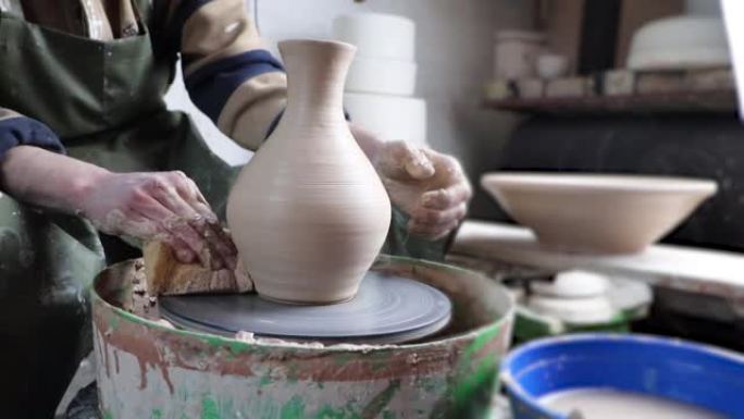 陶轮特写上的陶工手。古老的传统艺术，手工制作，粘土和陶瓷制作。柔和光线下的陶器车间
