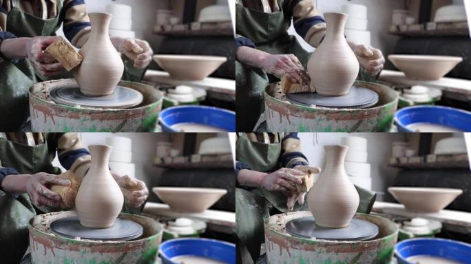 陶轮特写上的陶工手。古老的传统艺术，手工制作，粘土和陶瓷制作。柔和光线下的陶器车间
