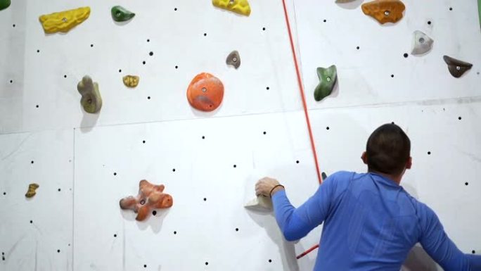 攀岩者在抱石攀岩墙上练习，里面有彩色钩子和保护线