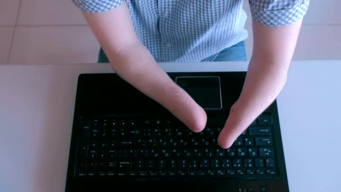 一个残肢残肢的残疾人正在笔记本电脑上打字，特写俯视图。