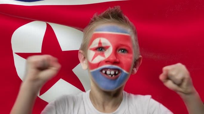 朝鲜国旗背景上的快乐粉丝。有着民族色彩的脸的快乐男孩。
