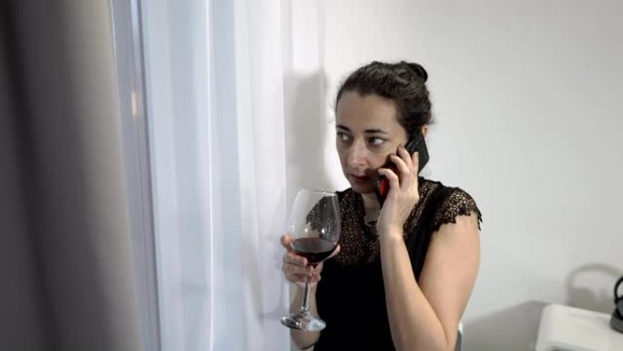 一个严肃的女人 -- 一位商务女士，在房间的窗户边打电话，喝杯红酒。特写。4K