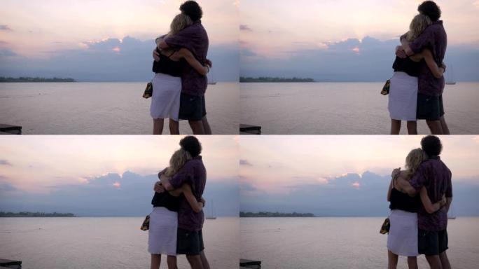 年长的美丽夫妇拥抱，同时俯瞰海洋上的日落