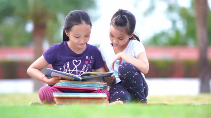 两个亚洲女孩在花园里读书